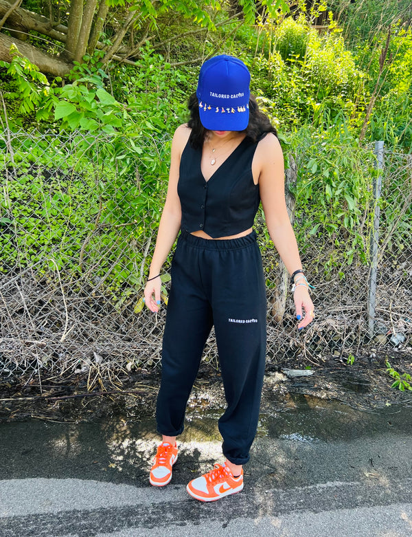 Tailored cactus girl in black sweatpants and purple charm trucker hat