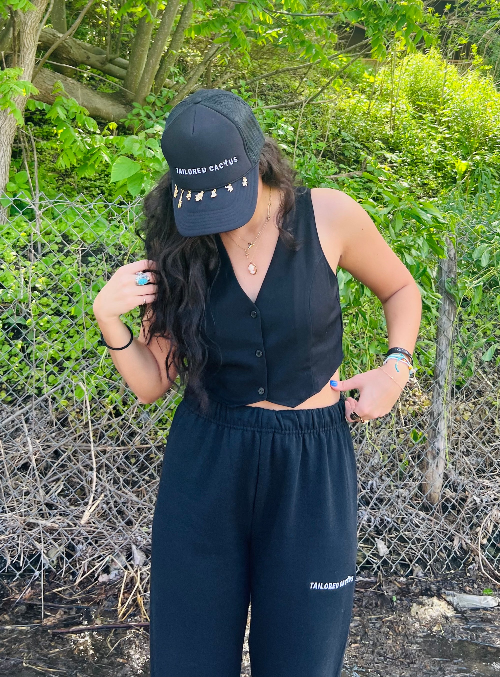 Tailored cactus girl in black sweatpants and black tailored cactus charm trucker hat 