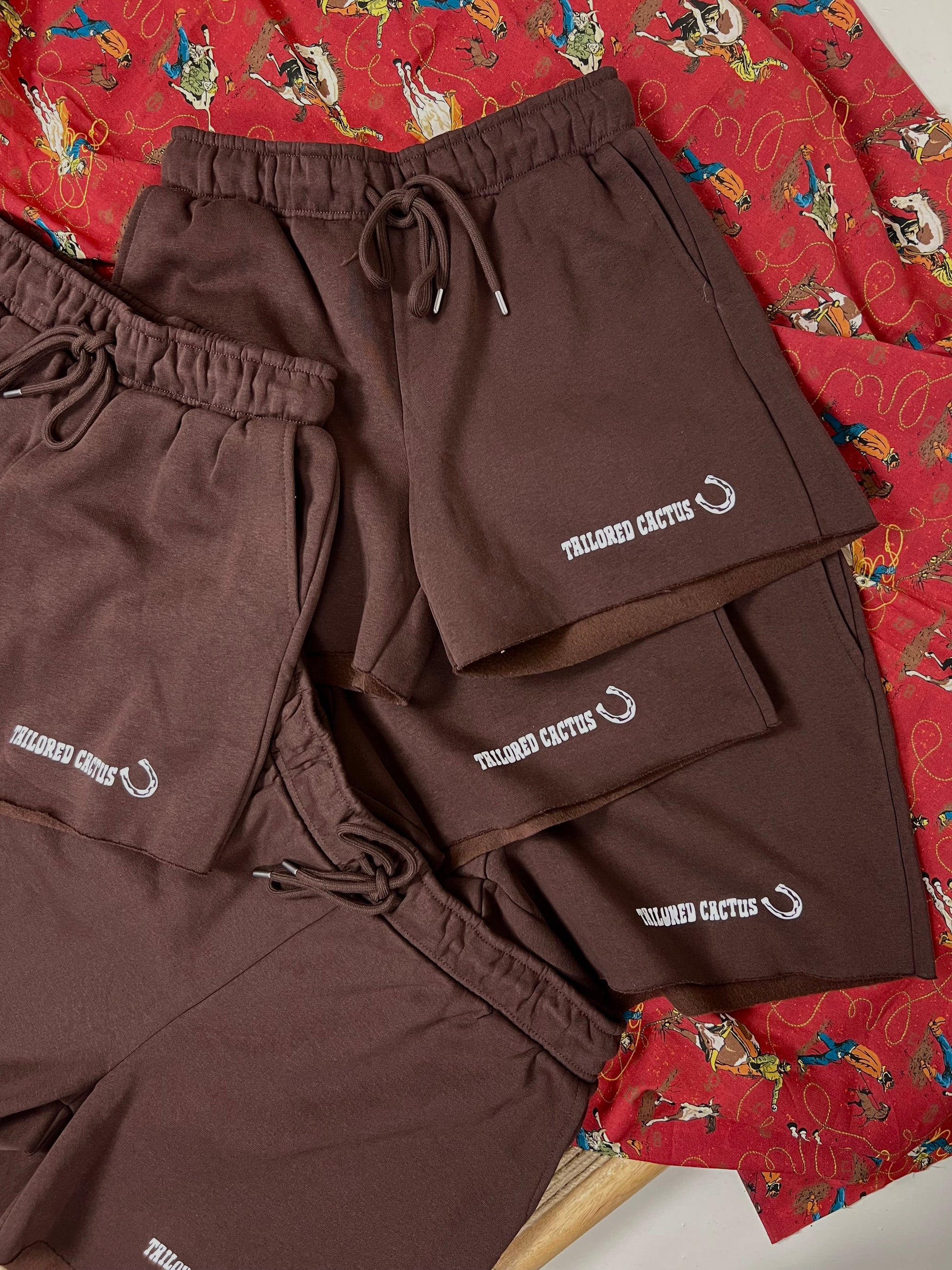 Brown shorts with a brand logo on a red patterned fabric background