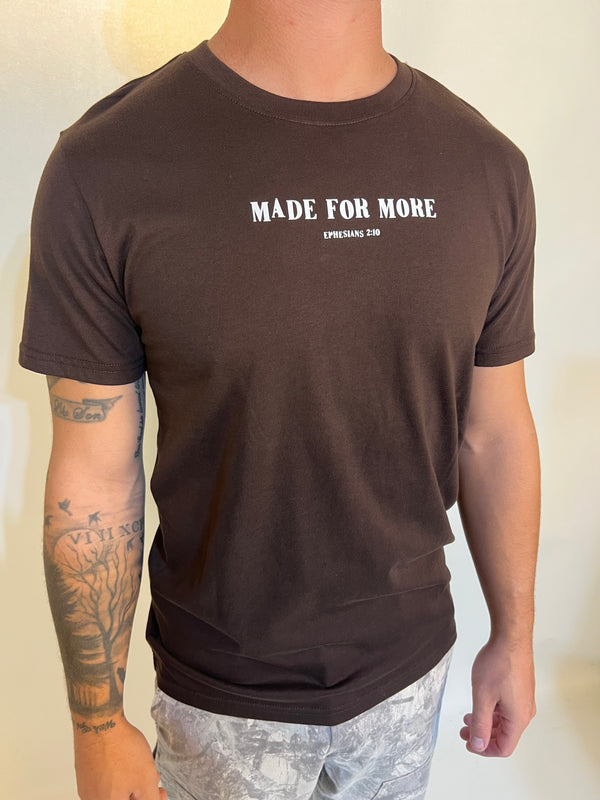 Person wearing a brown t-shirt with 'MADE FOR MORE' text on a plain background