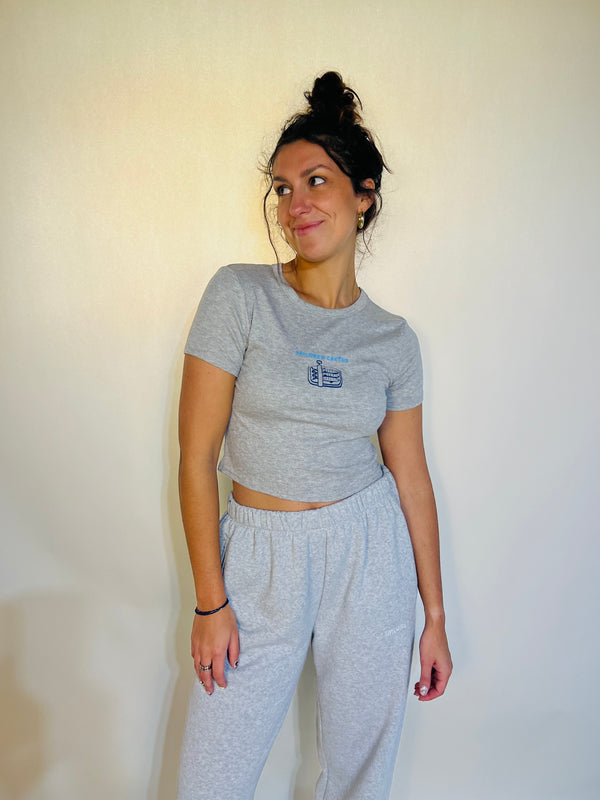 Woman wearing a gray crop top and pants against a plain background