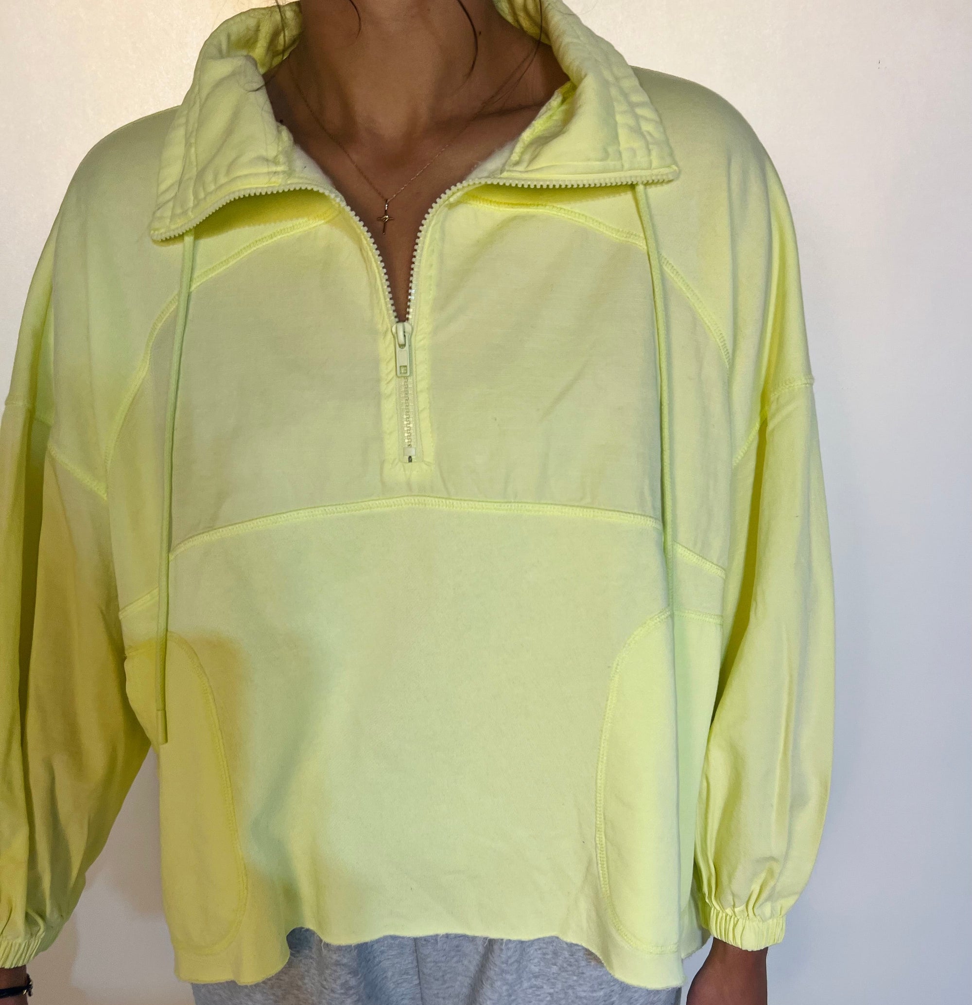 Person wearing a light green pullover with a quarter zip on a white background
