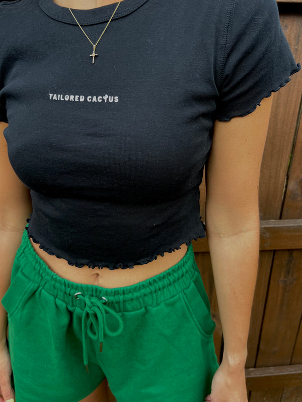 Tailored cactus girl in green shorts and black baby tee with lettuce edges