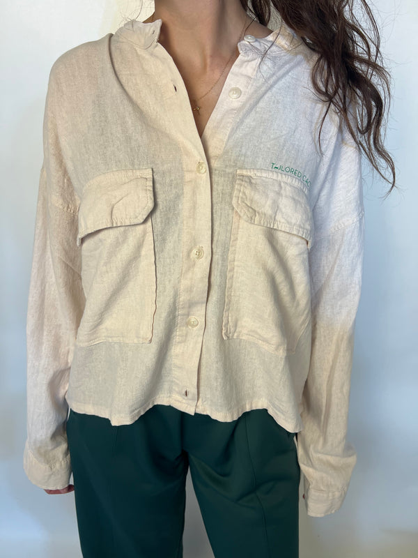 Girl in tailored cactus beige button up with ‘we love because he loved first’ on back