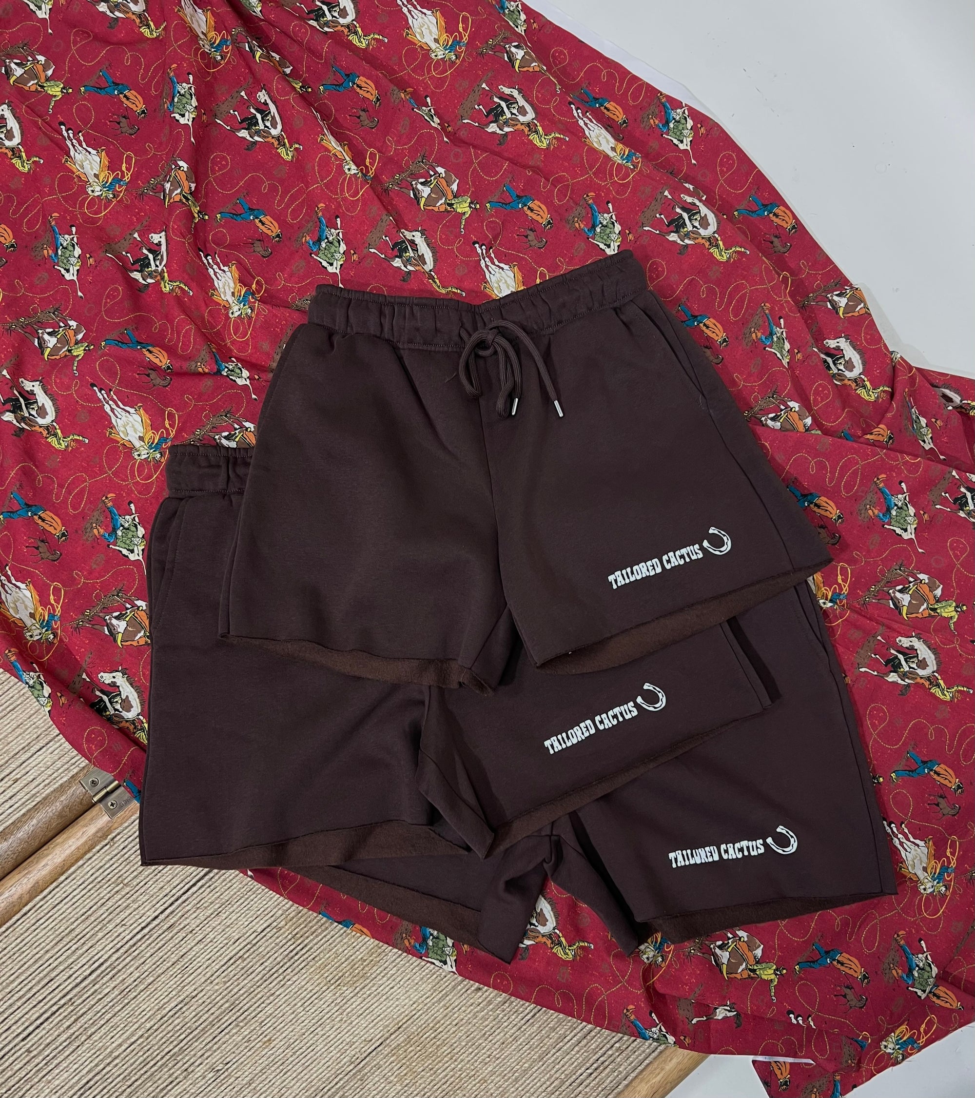Brown tailored cactus shorts on a red patterned fabric background