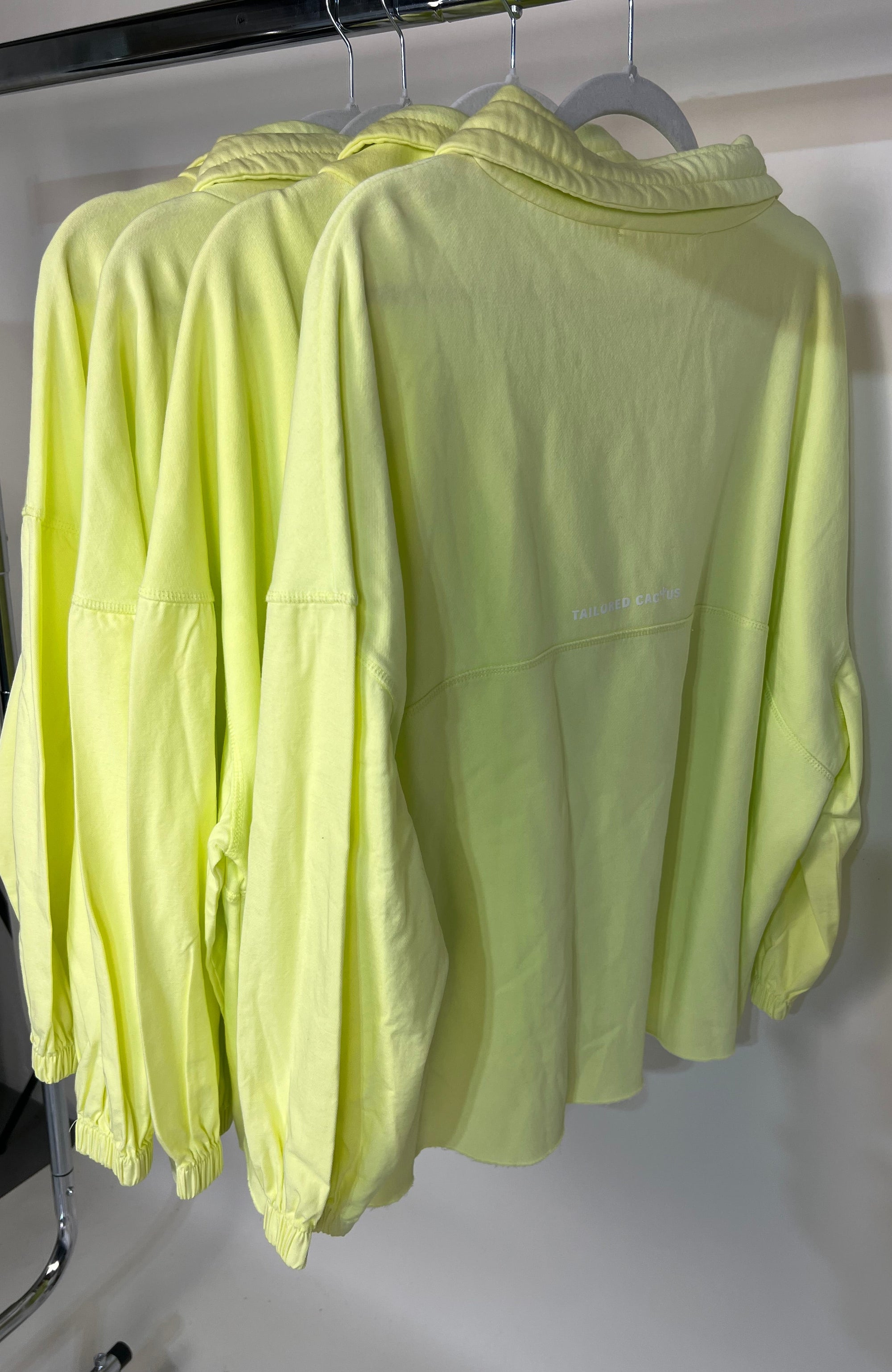 Stack of light green shirts on a metal rack against a white background