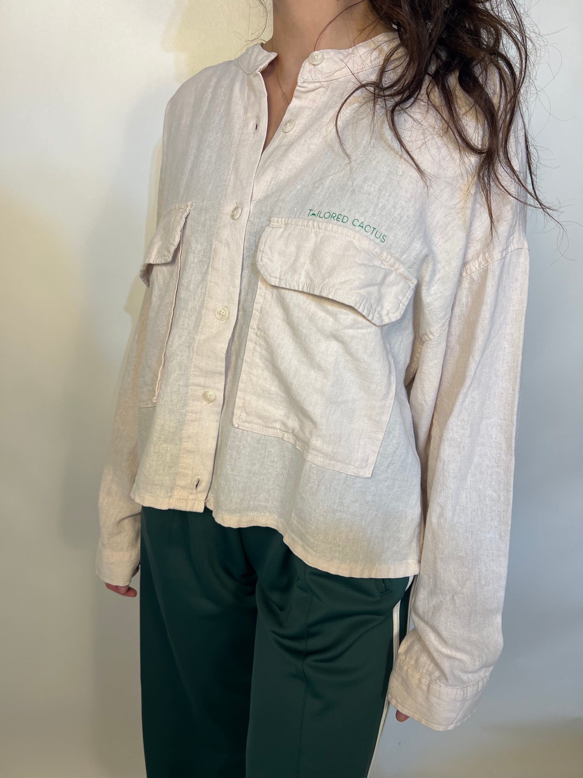 Girl in tailored cactus beige button up with ‘we love because he loved first’ on back